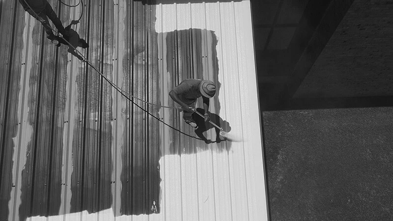Commercial roof contractor spraying a protective coating on top of an industrial or commercial roof
