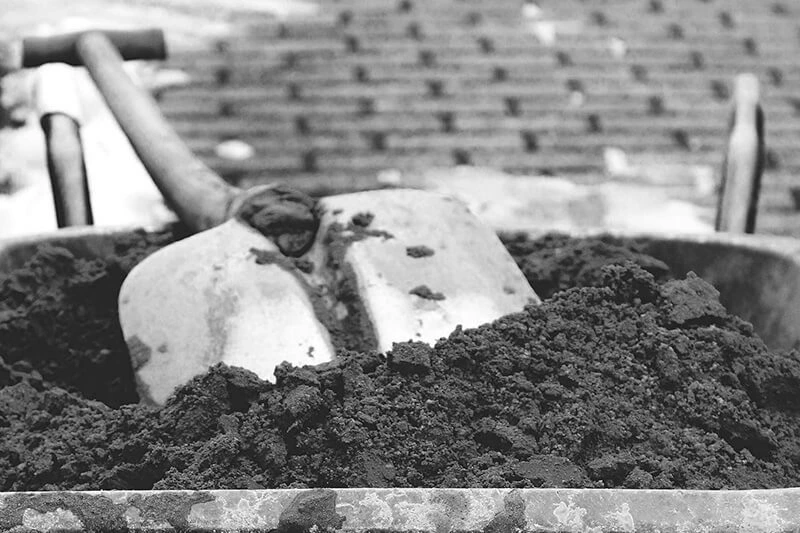 Close up view of a shovel in a wheelbarrow that's full of dirt for commercial landscaping services