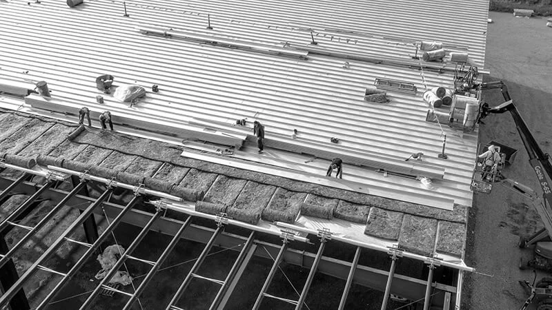 Large team installing new roof on massive commercial building for commercial roofing contractor