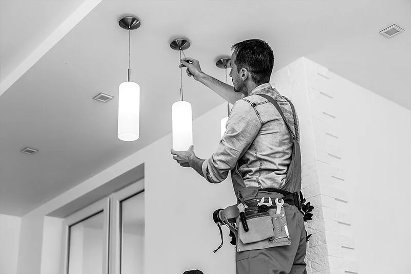 facility management group employee installing new pendant lights as part of a tenant improvement project