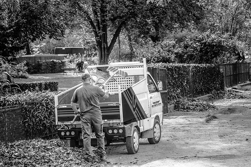 Man loading rakes and other tools into the back of large work truck for lawn care