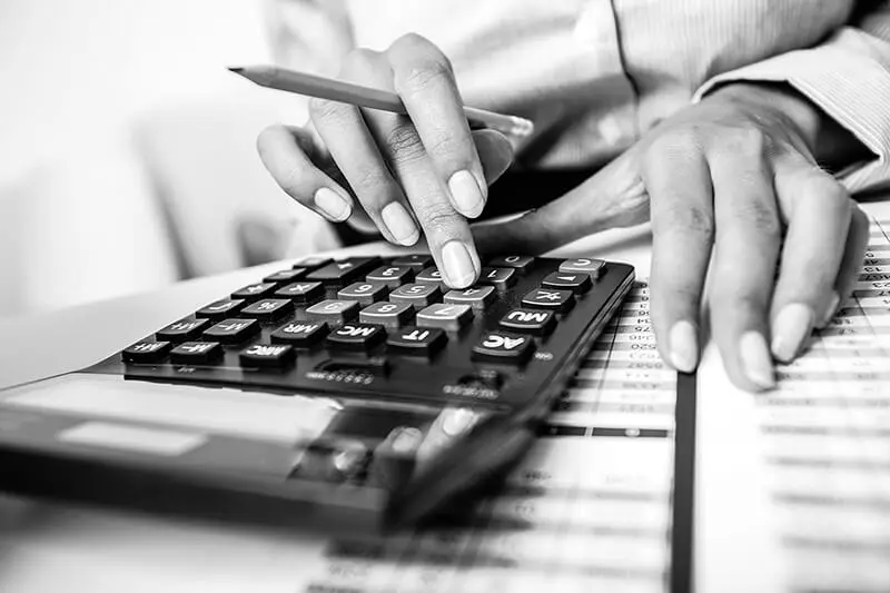 Woman doing calculations on large calculator, while holding a pencil calculating the cost of a subcontractor