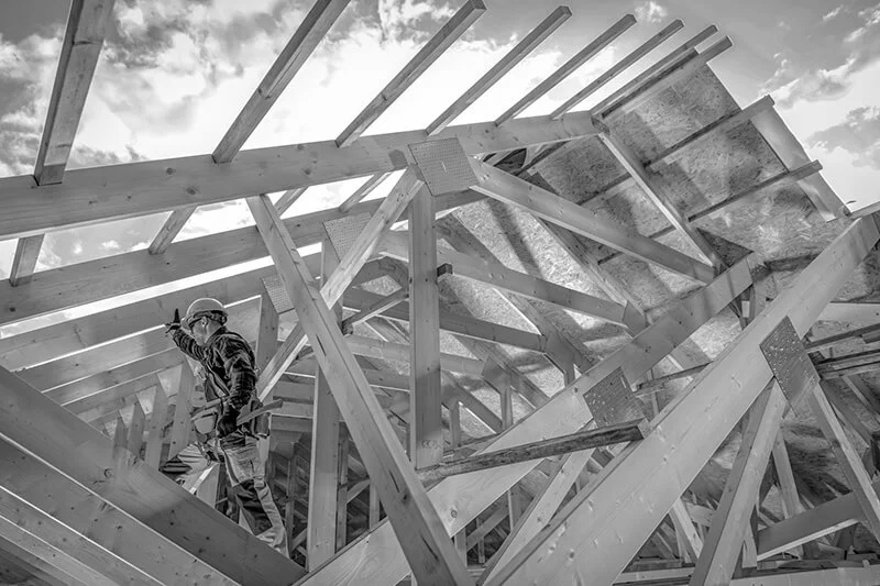 Man standing in newly-framed roof of industrial building doing construction framing